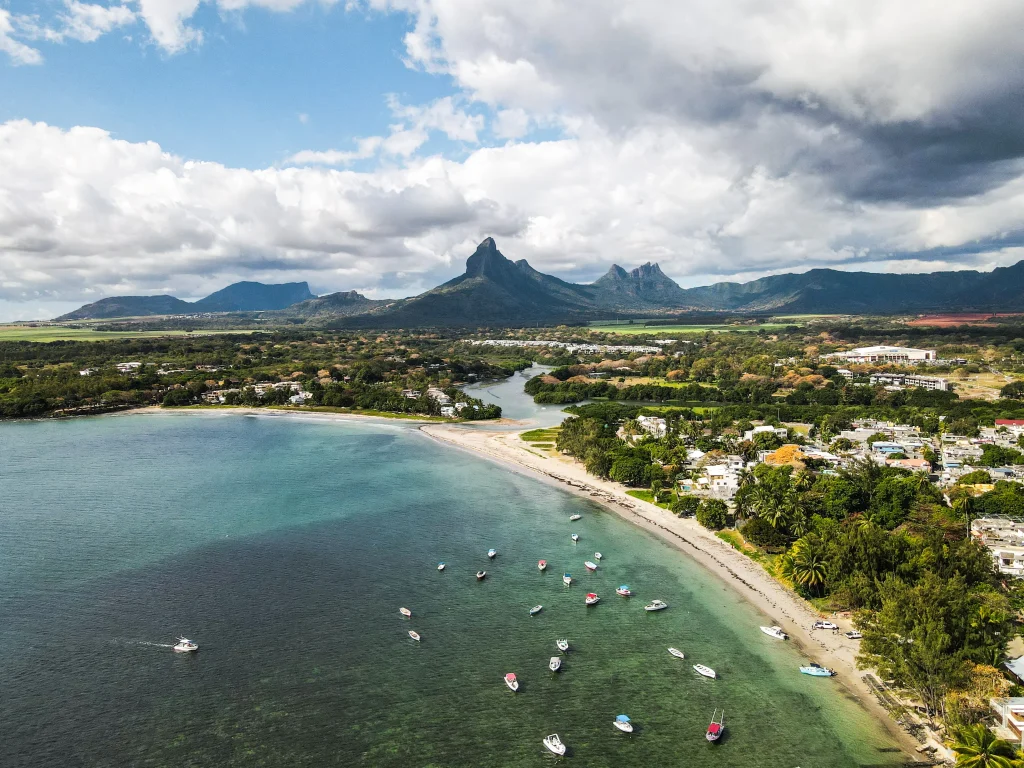 Aerial view of Mauritius coastline with turquoise lagoon, boats, and mountain landscape