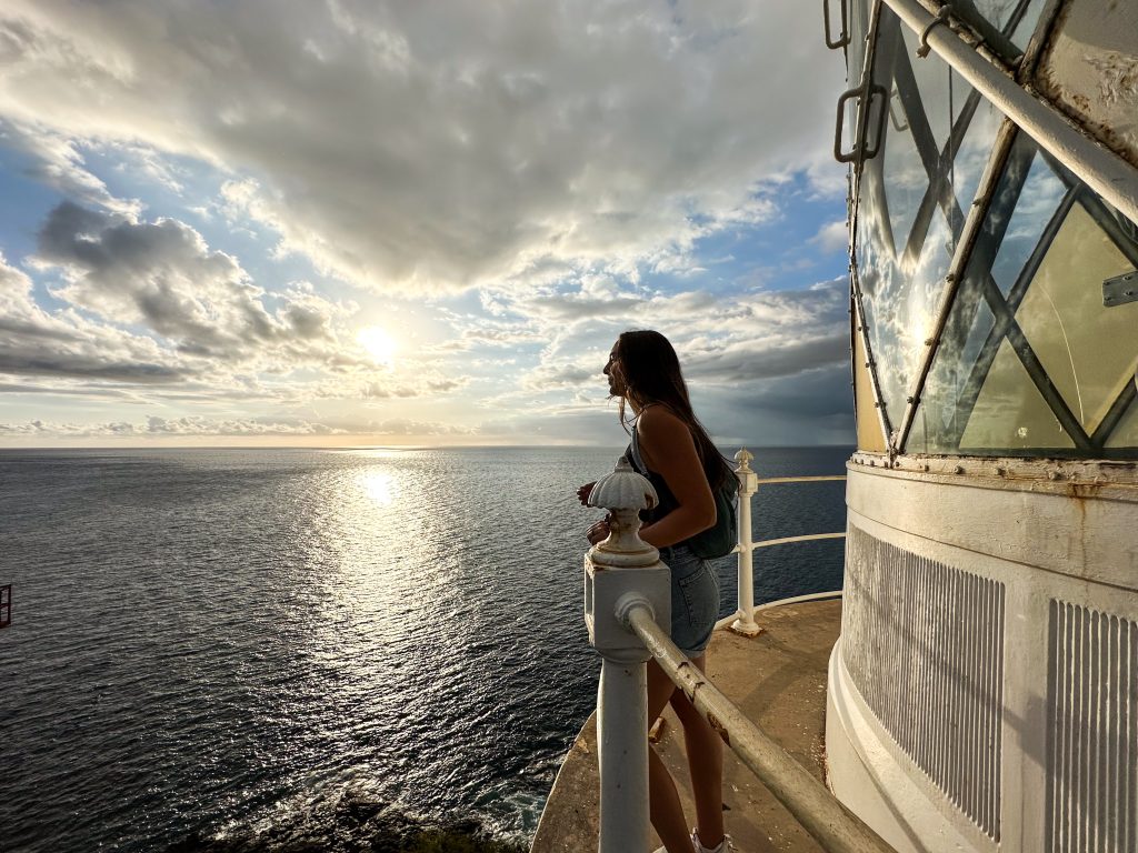Traveler overlooking the ocean from a lighthouse viewpoint in Mauritius during sunset while planning a scenic island itinerary.