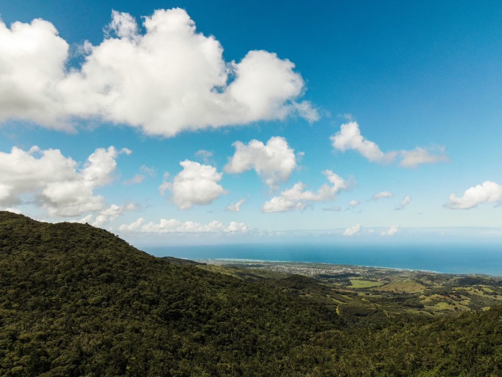 Panoramic mountain and coastal landscape in Mauritius showing lush forests, hills, and ocean views across the island’s travel regions.